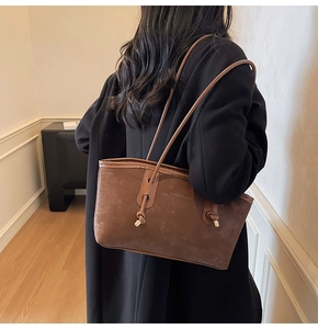 Detail of vintage brown suede tote bag with dual straps and fashion embossed text