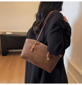 Detailed side view of a brown tote bag with fashion embossing and knotted shoulder strap