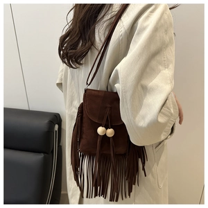 Detail of dark brown suede crossbody bag with long fringes and wooden beads