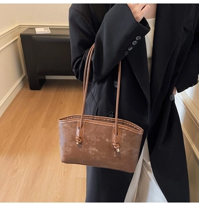 Close-up of vintage brown leather tote bag with unique knotted handles and textured finish