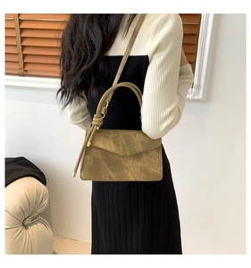 Detail of a brown faux leather crossbody bag with unique knot handle shown on a model