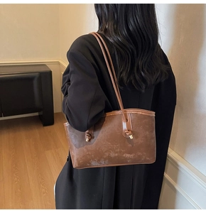 Detail of vintage brown leather tote bag with knotted shoulder straps and glossy finish