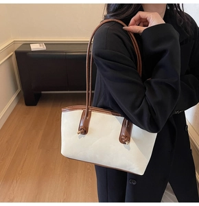 Detail of minimalist cream tote bag featuring brown leather trim and knotted strap knot