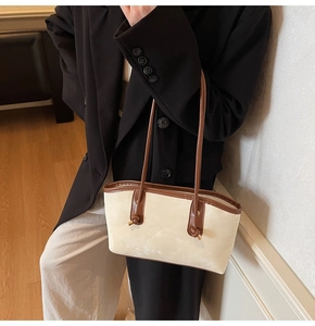 Detail view of the cream white tote bag with dark brown straps worn by a model