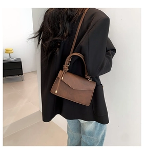 Detail of dark brown vintage faux leather handbag with gold clasp and top handle