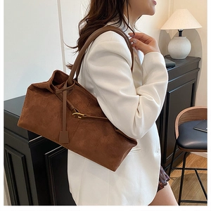 Detail of the dark brown suede tote bag with slim leather straps and matte texture