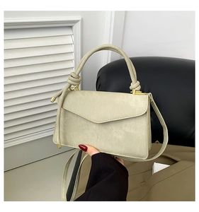 Detail of sage green crossbody bag with knot handle and gold hardware on textured faux leather