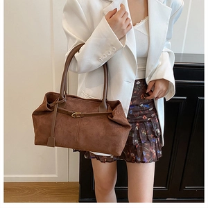 Detail of a brown matte tote bag featuring a golden metal buckle and twin shoulder straps