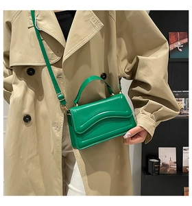 Detail view of a green leather crossbody bag with wave texture and gold hardware details