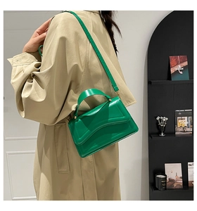 Detail of a bright green leather crossbody bag with wave flap and gold metal buckle