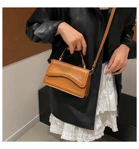 Brown leather crossbody bag with wave stitching shown on a model in a stylish outfit