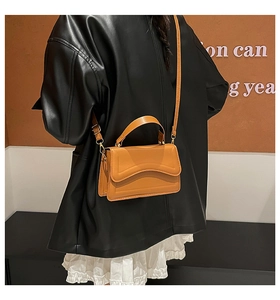 Close-up of caramel leather crossbody bag with wavy flap design and textured finish