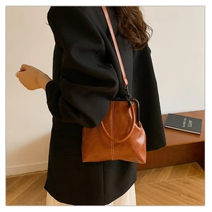 Close-up of vintage brown PU leather crossbody bag with metal kiss-lock and white stitching