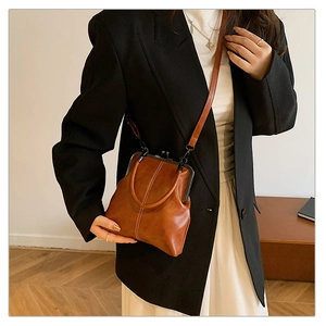 Brown vintage doctor bag shown on a model with a dark blazer and white dress
