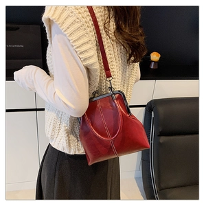 Detail of red vintage kiss-lock bag showing glossy leather texture and metal frame clasp