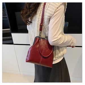 Detail of burgundy vintage clasp handbag with metal handles and white contrast stitching
