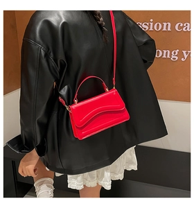 Detail of red quilted square bag with gold hardware worn over a black leather jacket