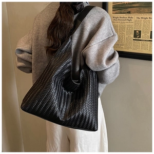 Close-up of black woven leather shoulder bag showing texture and oversized hobo design