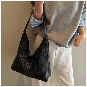Close-up of black woven leather texture on a large hobo bag for women fashion