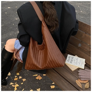 Close-up of brown woven texture hobo bag with leather strap in an autumn street setting