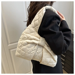 Detailed view of the large quilted bow shoulder bag in cream white on a model shoulder
