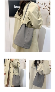 Detail view of grey bucket bag showing contrast white stitching and gold hardware