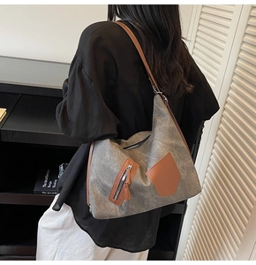 Detail of grey canvas tote bag with brown leather stitching and zipped front pocket