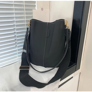 Detail of black bucket bag featuring white contrast stitching and gold-tone hardware