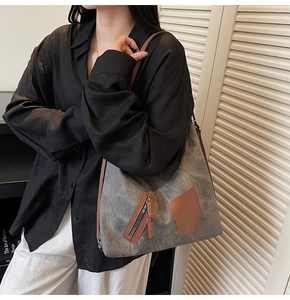Detail of gray canvas tote bag with brown leather accents and diagonal front zipper pocket