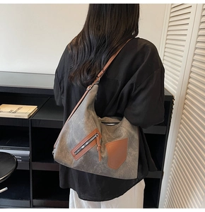 Close-up of hobo bag with grey canvas material and brown leather trim details