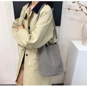 Detail view of grey bucket bag showing white contrast stitching and matte texture