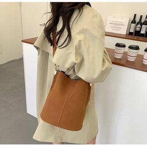 Detail of vintage brown bucket bag showing adjustable strap and contrast stitching
