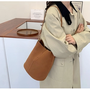 Detail of caramel leather bucket bag with white contrast stitching and shoulder strap