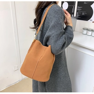 Detail of tan bucket bag featuring white contrast stitching and matte synthetic leather