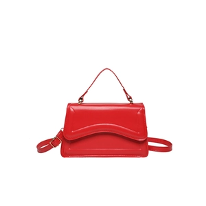 Sac bandoulière rouge chic avec rabat ondulé et boucle dorée sur fond blanc neutre