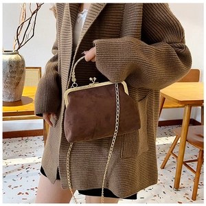 Détail du sac à main marron foncé en suède avec cadre doré et bandoulière chaîne