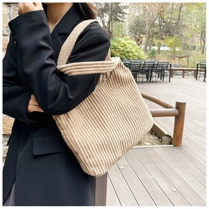 Primer plano detallado de un bolso tote de pana beige que muestra su textura y gran capacidad