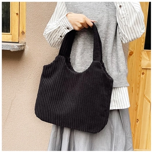 Primer plano de la textura del bolso tote de pana negra sostenido por la modelo