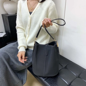 Chic black bucket bag with white contrast stitching and gold metal hardware details