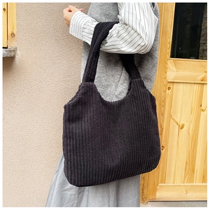 Primer plano detallado de un bolso de hombro grande de pana negra con textura de canalé