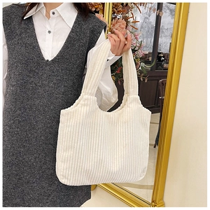 Detalle de la textura de pana y el asa resistente en un bolso tote de color crema
