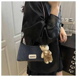 Détail du sac en jean avec bandoulière en cuir marron et breloque ours en peluche blanc