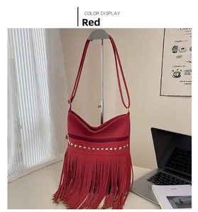 Dettaglio della borsa a tracolla rossa con borchie dorate e lunghe nappe decorative