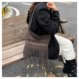 Détails d'un sac à main marron avec franges en cuir et rivets carrés dorés de style boho