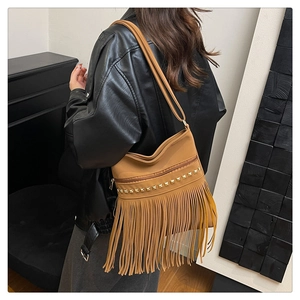 Détail du sac à main marron à franges avec clous dorés porté avec une veste en cuir noir
