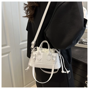 Detail of white mini bucket bag with crocodile texture and drawstring inner pouch