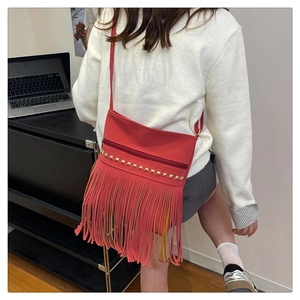 Dettaglio di una borsa rossa con frange decorata con borchie dorate e texture opaca