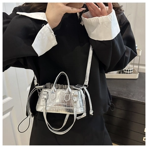 Détail du mini sac seau argenté à motif crocodile avec lettrage mode et cordon de serrage