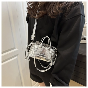 Detail of silver crocodile-embossed bucket bag with metallic texture and drawstring inner