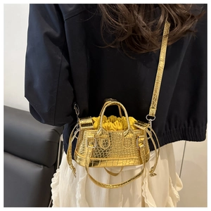 Back view of a mini golden crocodile texture handbag styled with a white pleated skirt